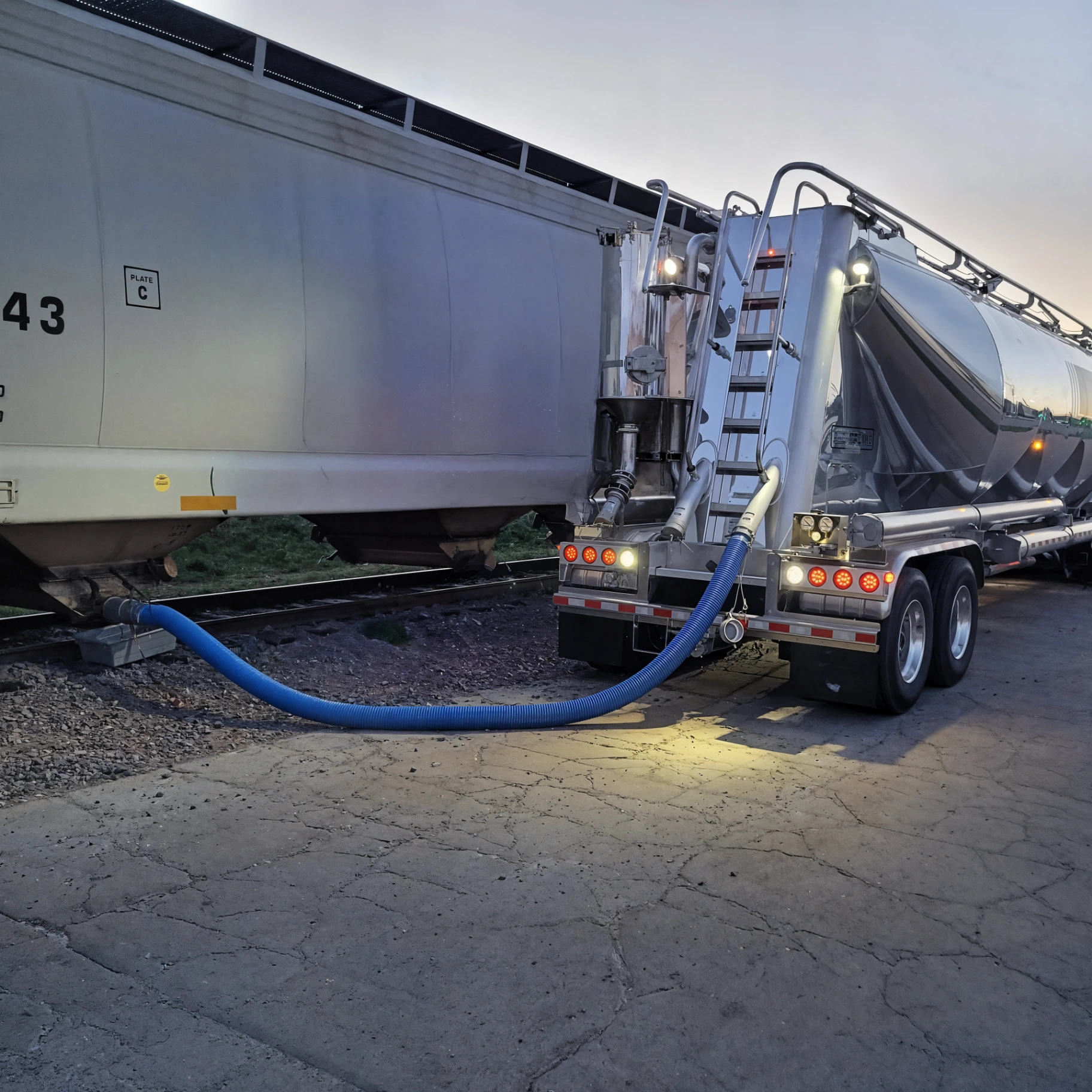 Pneumatic dry-bulk tanker positioned at a rail transload