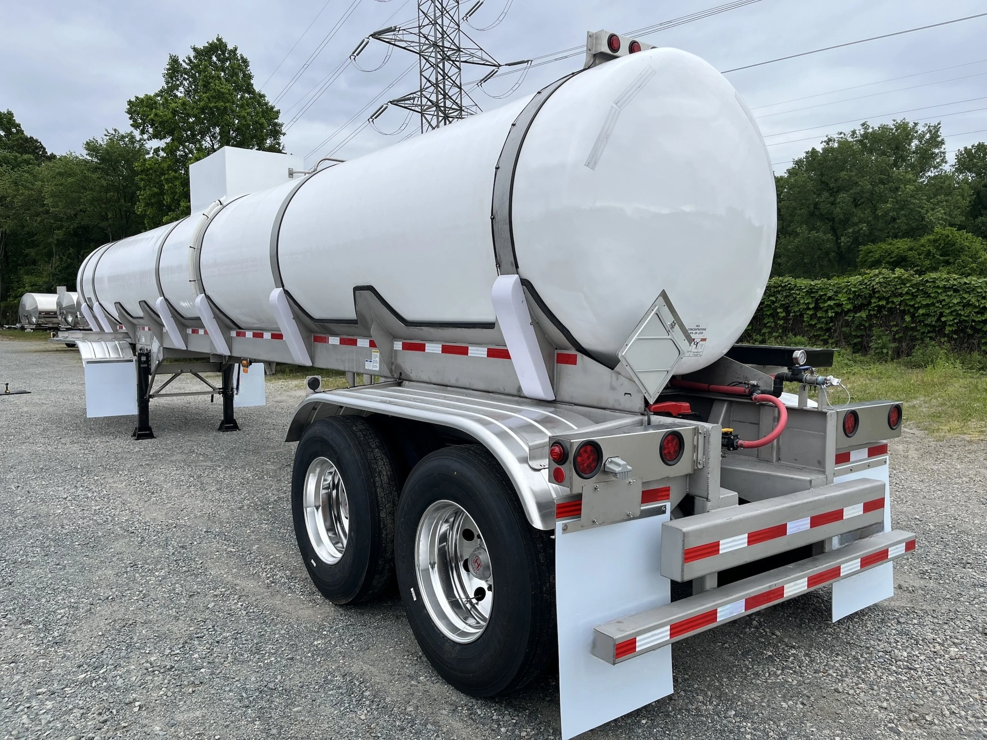 White food-grade liquid tanker trailer staged on a paved yard